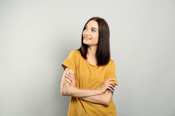 Obraz premium Portrait of pretty young woman with gorgeous chestnut hair and charming smile on light grey background