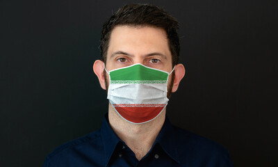 Man wearing Iranian flag protective medical face mask. He looks worried and concerned. Coronavirus concept in Iran with black background.