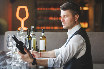 Sommelier looks at bottle of expensive wine in restaurant