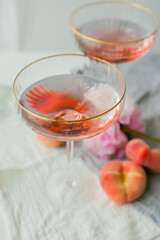 Beautiful glass with pink champagne, peaches on the background. Peonies. Aesthetic.