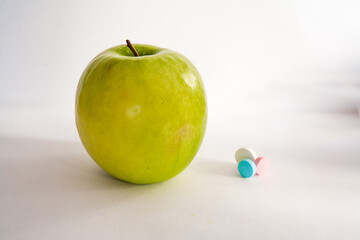 Green apple or vitamin pills on a white background. Healthy eating, diet, lifestyle concept, treatment choice concept
