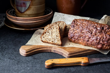 Bread with sunflower and flax seeds on a wooden cutting board on a black background