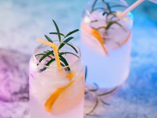 alcoholic drink with ice or cocktail gin and tonic with lemon and rosemary, stylish color lighting