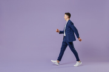 Fototapeta na wymiar Full size body length side view young successful employee business man lawyer 20s wears formal blue suit white t-shirt work in office move stroll isolated on pastel purple background studio portrait.