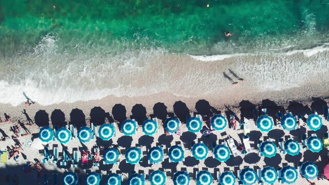 Aerial overhead view of lined beach umbrellas on a tropical beach. Slow motion