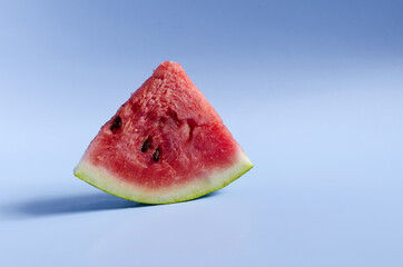 A piece of sweet watermelon on a blue background. A ripe watermelon on a colored background is a place for text.