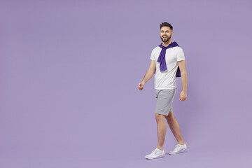 Fototapeta na wymiar Full size body length happy fun young brunet man 20s wear white t-shirt purple shirt go step walk pace stroll isolated on pastel violet background studio portrait. People emotions lifestyle concept