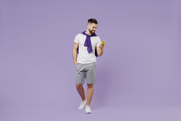 Fototapeta na wymiar Full size body length young brunet man 20s wear white t-shirt purple shirt hold in hand use mobile cell phone talk speak on mobile cell phone isolated on pastel violet background studio portrait