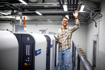 Portrait of professional graphic designer or engineer waving to the camera and checking production...