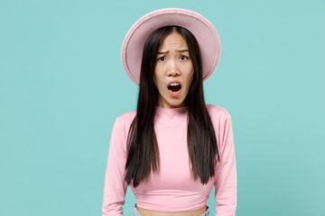 Fototapeta premium Amazed shocked frightened young brunette asian woman 20s with open mouth wears pink clothes hat look camera isolated on pastel blue color background studio portrait. People emotions lifestyle concept