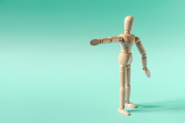 The figure of a wooden man with an outstretched arm on a green background. The figure of a wooden man on a colored background of the mine space