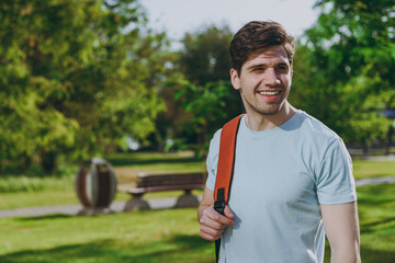 Happy student man in blue t-shirt backpack hold hand at forehead look far away distance walk rest relax in spring green city park go down lawn sunshine outdoor on nature Education high school concept.