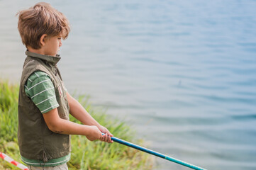 A boy with a fishing rod fishes on the lake,a river,a sea