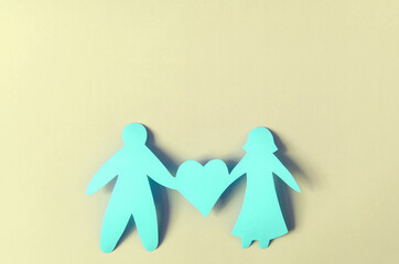 Bright red figures of two people and a heart on a colored background. The concept of a happy relationship. Cardboard figures of people	