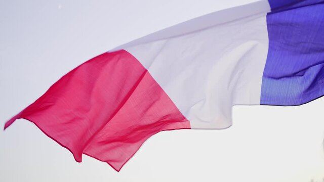 Flag of France in the wind. A woman holds the national symbol of her country