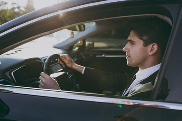 Side profile view young serious driver confident caucasian businessman man 20s wear black dinner...