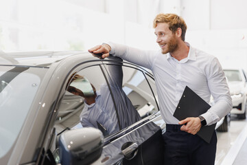 Man pensive customer male buyer client in white shirt hold clipboard paper document lean on car...