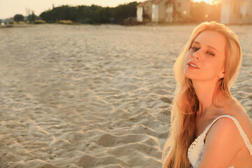 Beautiful young woman on sandy beach, space for text