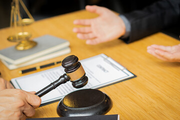 Consulting of businessmen and male lawyers or judges with team meetings with clients. Legal services concept with hammer and scales with contract documents with laptop on table.