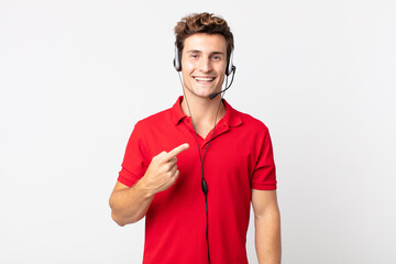 young handsome man looking excited and surprised pointing to the side. telemarketer concept