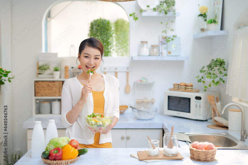 Wall mural woman eating healthy salad in modern kitchen