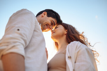 Bottom view close up charming smiling satisfied happy young couple two friends family man woman 20s in white clothes boyfriend hug girlfriend enjoy together touch noses on blue light sky background