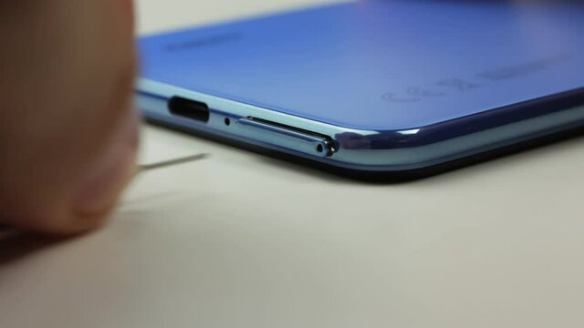Close-up of a man's hand removing a tray with two nano-SIM cards from a modern smartphone