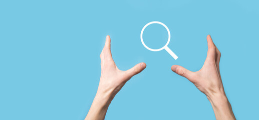 Male hand holding magnifying glass ,search icon on blue background. Concept search engine optimization, customer support.Browsing Internet Data Information.Networking Concept.