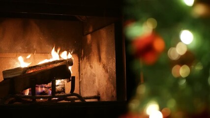 Christmas tree lights by fire in fireplace, New Year or Xmas decoration of pine or fir with red balls. Fireside on winter christmastime holiday. Cozy place by firewood. Seamless looped cinemagraph.