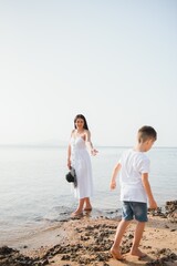 Happy mother and son walk along the ocean beach having great family time on vacation on Pandawa Beach, Bali. Paradise, travel, vacation concept