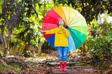 Child playing in autumn rain. Kid with umbrella.