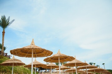Umbrella and deck chair around outdoor swimming pool in hotel resort with sea ocean beach and coconut palm tree