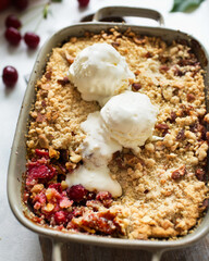 A traditional English dessert is cherry crumble with ice cream. Cherry pie with almonds on a white background. Rustic berry cake with a ball of ice cream and a fresh harvest of berries