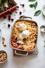 A traditional English dessert is cherry crumble with ice cream. Cherry pie with almonds on a white background. Rustic berry cake with a ball of ice cream and a fresh harvest of berries