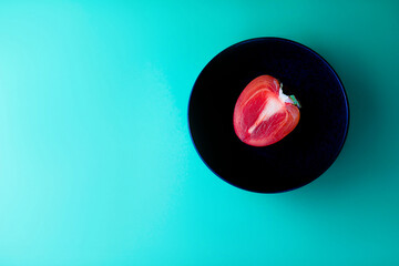 Persimmon on a black plate. Green background. Abstract background.
