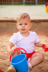 Adorable toddler girl playing with sand on sandbox in playground