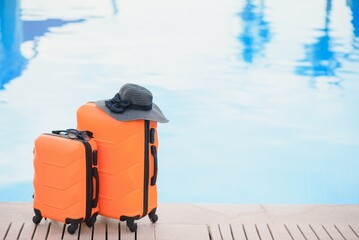 Travel, summer holidays and vacation concept. pink suitcase with hat on background of hotel pool area in Egypt.