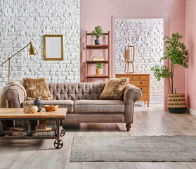 Grey and brown classic sofa with blanket and pillow in front of the white brick and pink wall background, gold lamp, frame and bookshelf, wooden cabinet style, home interior concept.