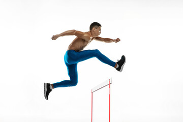 Steeplechase. Young male athlete, runner running, jumping isolated on white studio background. Muscular, sportive man. Concept of sport, healthy lifestyle
