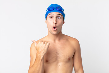 young handsome man looking astonished in disbelief. swimmer concept