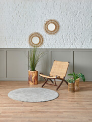 Wicker chair in front of the white brick and brown wall, mirror and botanic plant gold vase.