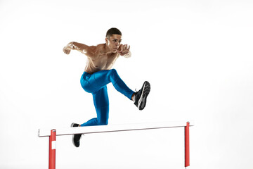 Steeplechase. Young male athlete, runner running, jumping isolated on white studio background. Muscular, sportive man. Concept of sport, healthy lifestyle