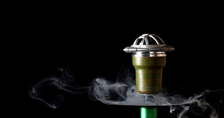 Hookah bowl on a black background with smoke. space for text