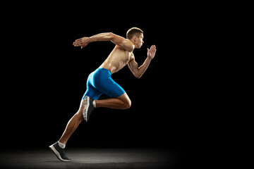 One Caucasian professional male athlete, runner training isolated on dark studio background. Muscular, sportive man. Concept of sport, healthy lifestyle