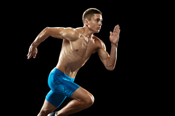 One Caucasian professional male athlete, runner training isolated on dark studio background. Muscular, sportive man. Concept of sport, healthy lifestyle