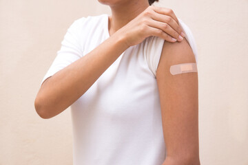 Woman white shirt showing her arm after receiving vaccine shot on White background.