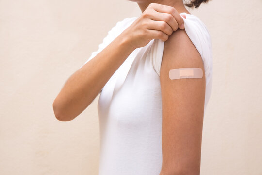 Woman white shirt showing her arm after receiving vaccine shot on White background.