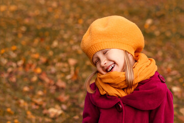 Autumn Dreamy little girl in a yellow beret and autumn clothes on an autumn background. Smiling kid play in autumn park.