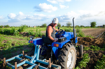 The farmer works in the field with a tractor. Agroindustry and agribusiness. Farm field work cultivation. Farming machinery. Plowing and loosening ground. Crop care, soil quality improvement.