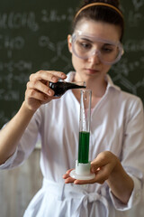 female scientist doing scientific tests with chemical flask and liquid in school laboratory